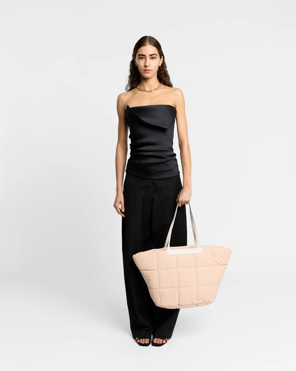 On-body picture of a woman holding the Porter Basque Tote Bag in Cameo Rose by Vee Collective, wearing a minimalistic outfit against a clean studio background.