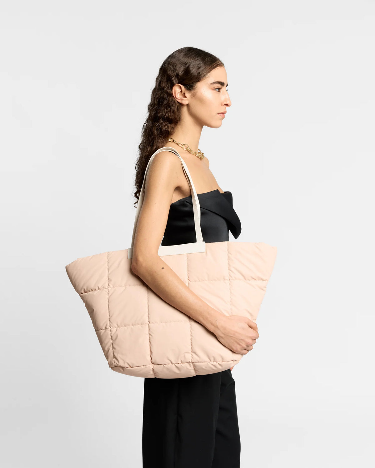 On-body picture of a woman carrying the Porter Basque Tote Bag in Cameo Rose by Vee Collective, wearing a minimalistic outfit against a clean studio background.