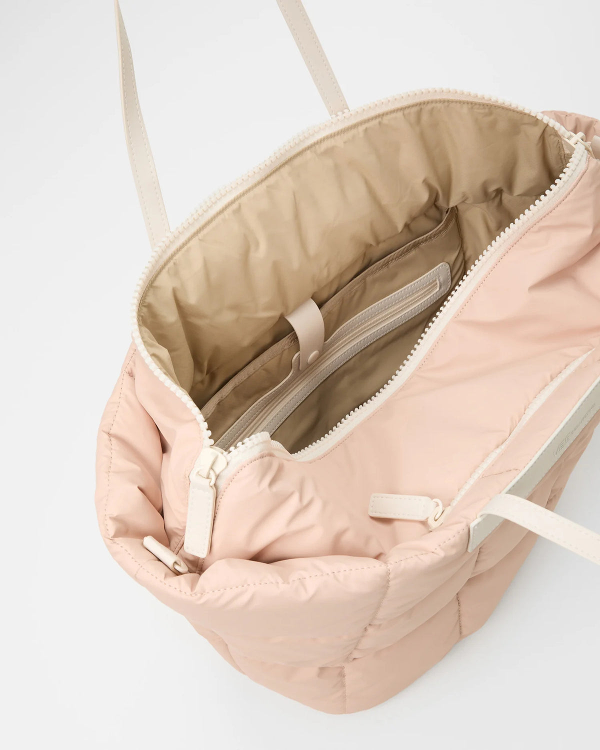 Open Vee Collective Porter Basque Tote Bag in Cameo Rose, showing the quilted exterior, top zipper, and interior compartments of the tote bag.