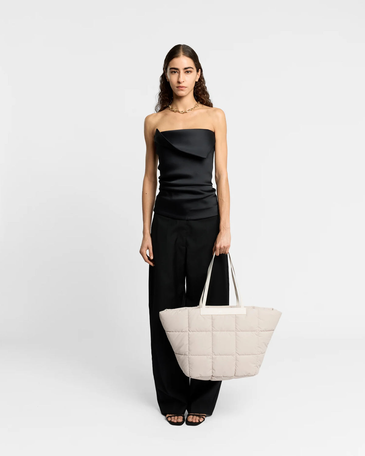 On-body picture of a woman carrying the Porter Basque Tote Bag in Soft Taupe by Vee Collective, wearing a minimalistic outfit against a clean studio background.
