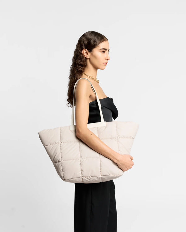 On-body picture of a woman carrying the Porter Basque Tote Bag in Soft Taupe by Vee Collective, wearing a minimalistic outfit against a clean studio background.