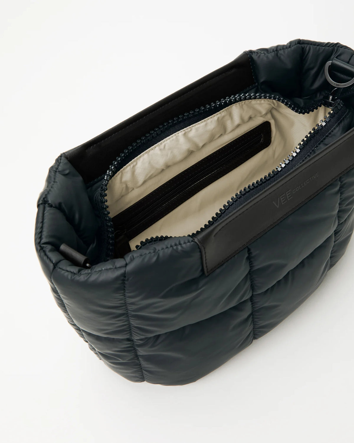 Open Vee Collective Porter Basque Clutch Bag in Dark Navy, showing the quilted exterior, top zipper, and interior compartments of the tote bag.