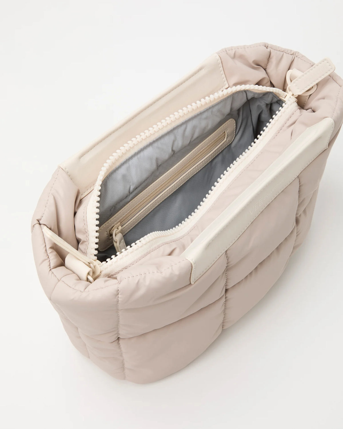 Open Vee Collective Porter Basque Clutch Bag in Soft Taupe, showing the quilted exterior, top zipper, and interior compartments of the tote bag.