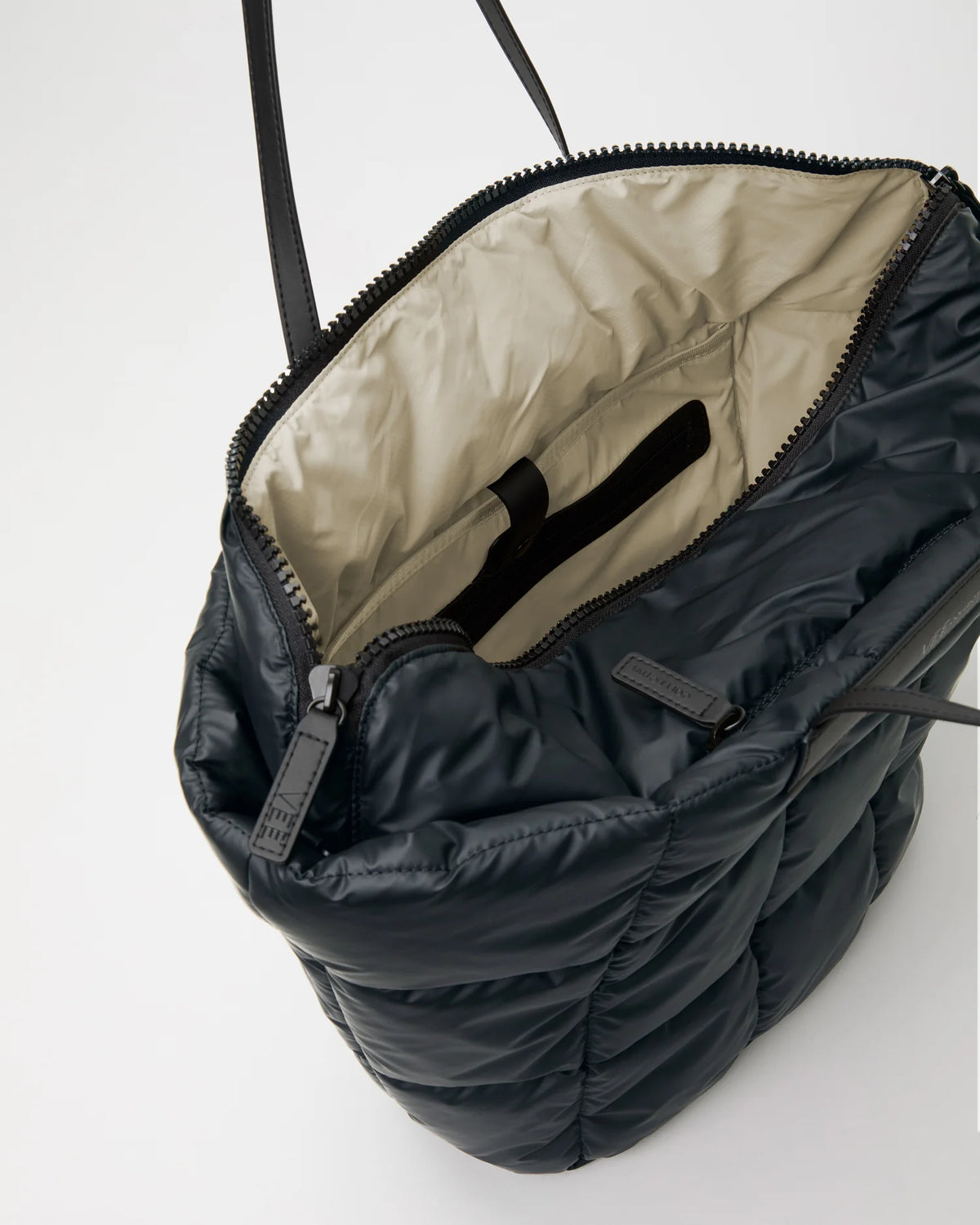 Open Vee Collective Porter Basque Tote Bag in Dark Navy, showing the quilted exterior, top zipper, and interior compartments of the tote bag.