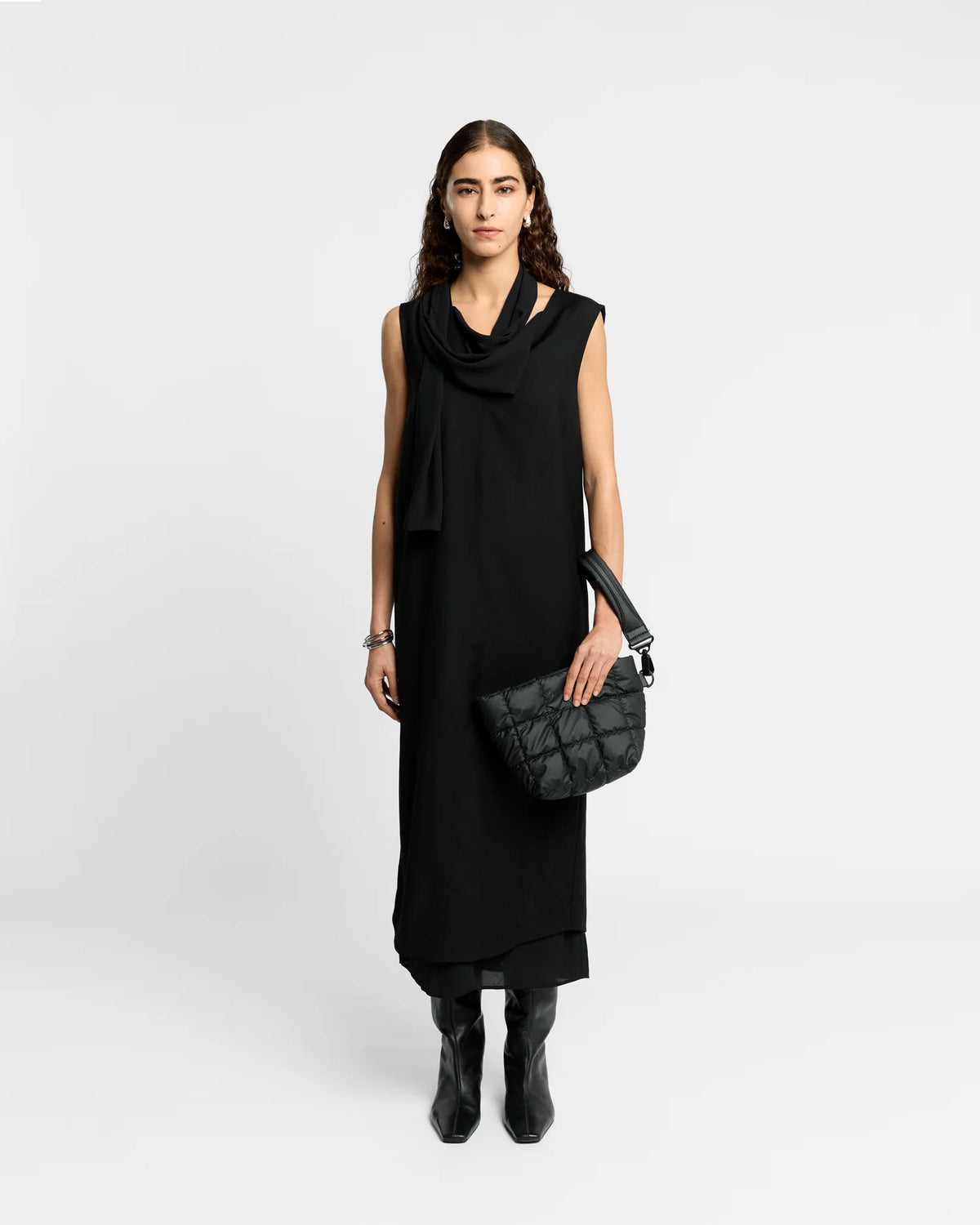 Woman wearing a clean outfit holding the Vee Collective Porter Clutch Bag in Black, shown with its attachable wristlet.