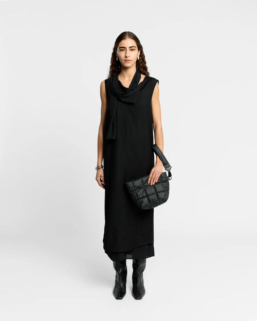 Woman wearing a clean outfit holding the Vee Collective Porter Clutch Bag in Black, shown with its attachable wristlet.