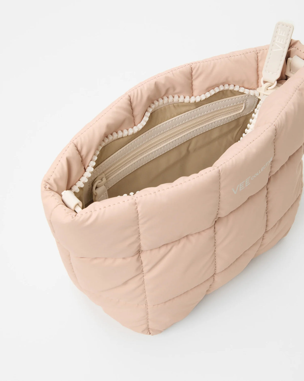 Open Vee Collective Porter Clutch Bag in Cameo Rose, showing the quilted exterior, top zipper, and interior compartments of the tote bag.