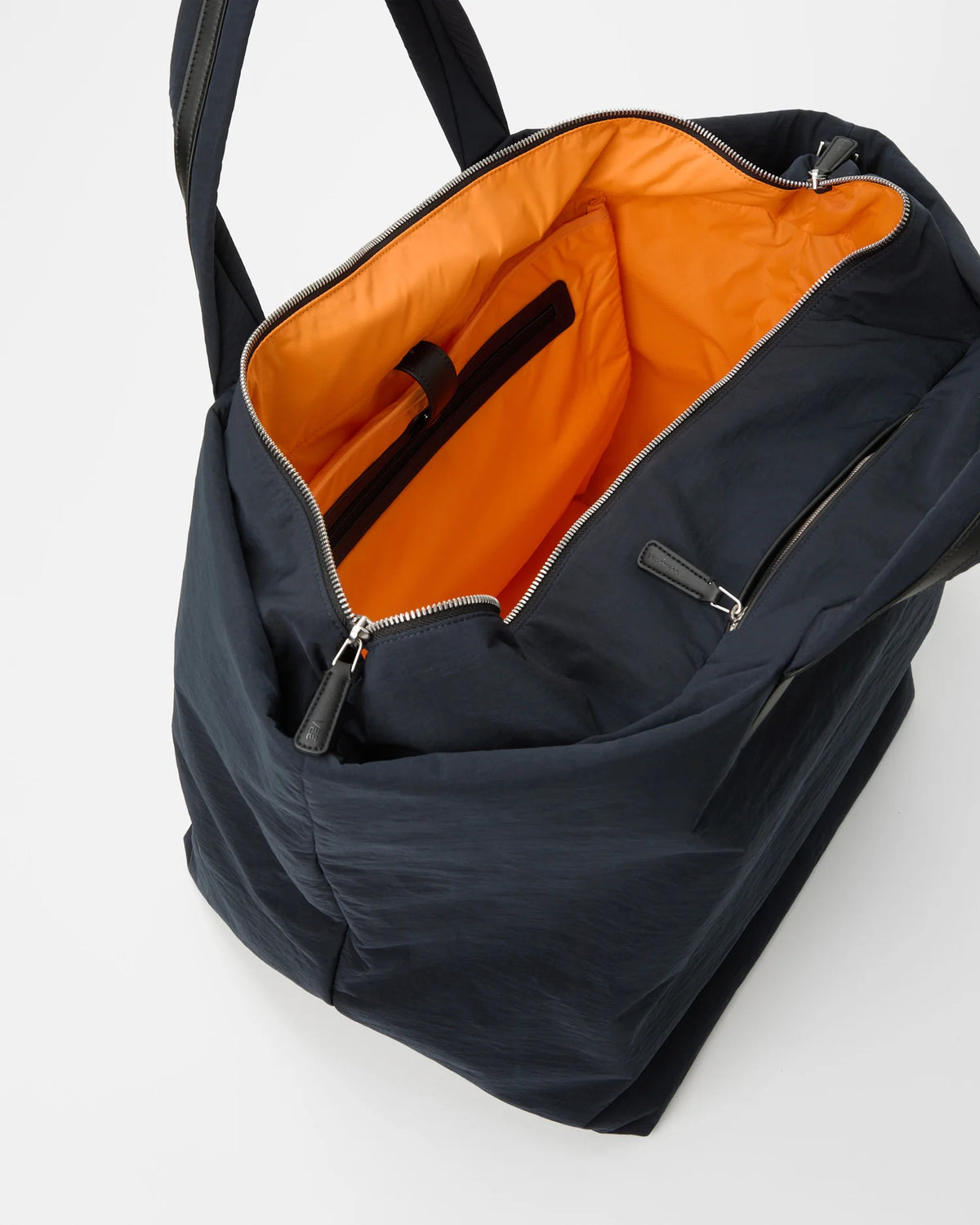 Open Vee Collective Porter Essence Weekender in Midnight Trench, showing the quilted exterior, top zipper, and orange interior of the Tote bag.
