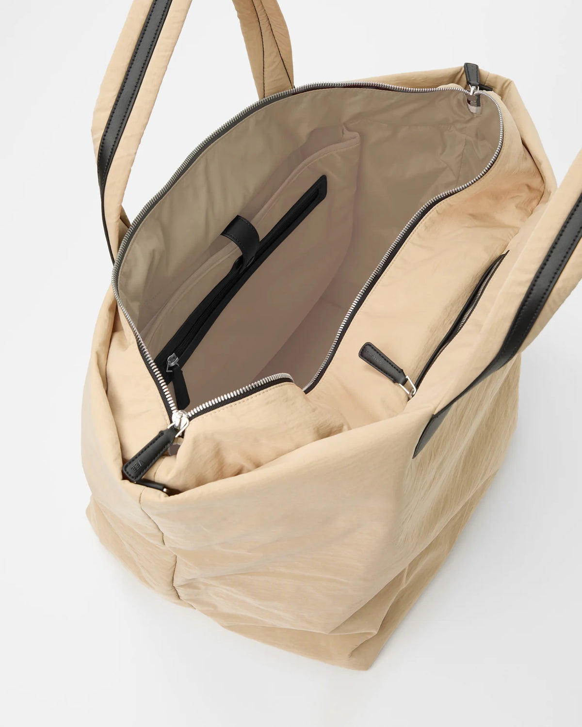 Beige Weekender bag with black trim handles open to reveal tan interior and inner zip pocket.
