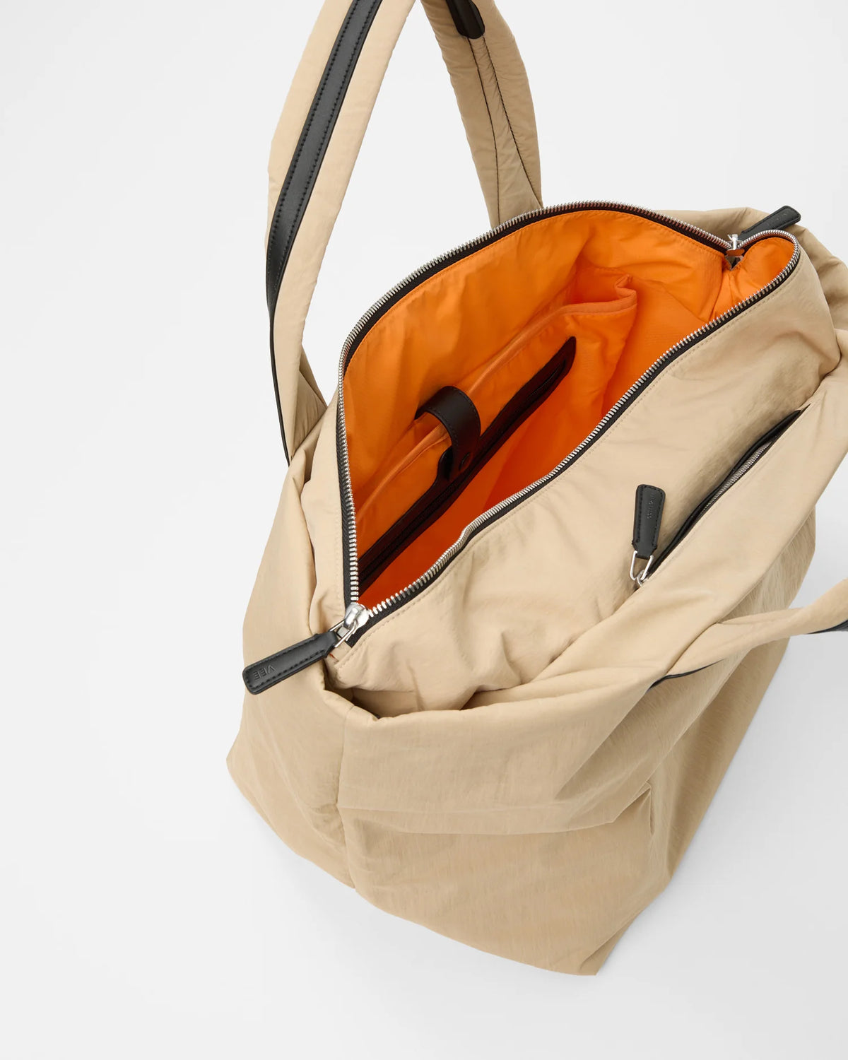 Open Vee Collective Porter Essence Small in Beige Trench, showing the quilted exterior, top zipper, and orange interior of the Tote bag.