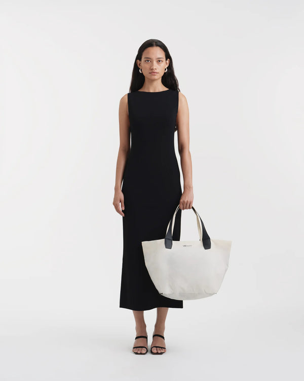 Woman holding the Vee Collective Porter Essence Medium Tote Bag in off-white with her arm extended in front of her body, shown as an on-body styling view.
