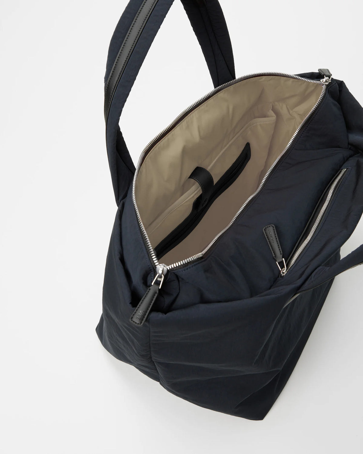 Essence Tote Medium in midnight navy, zipper open to reveal beige interior and inner pocket.