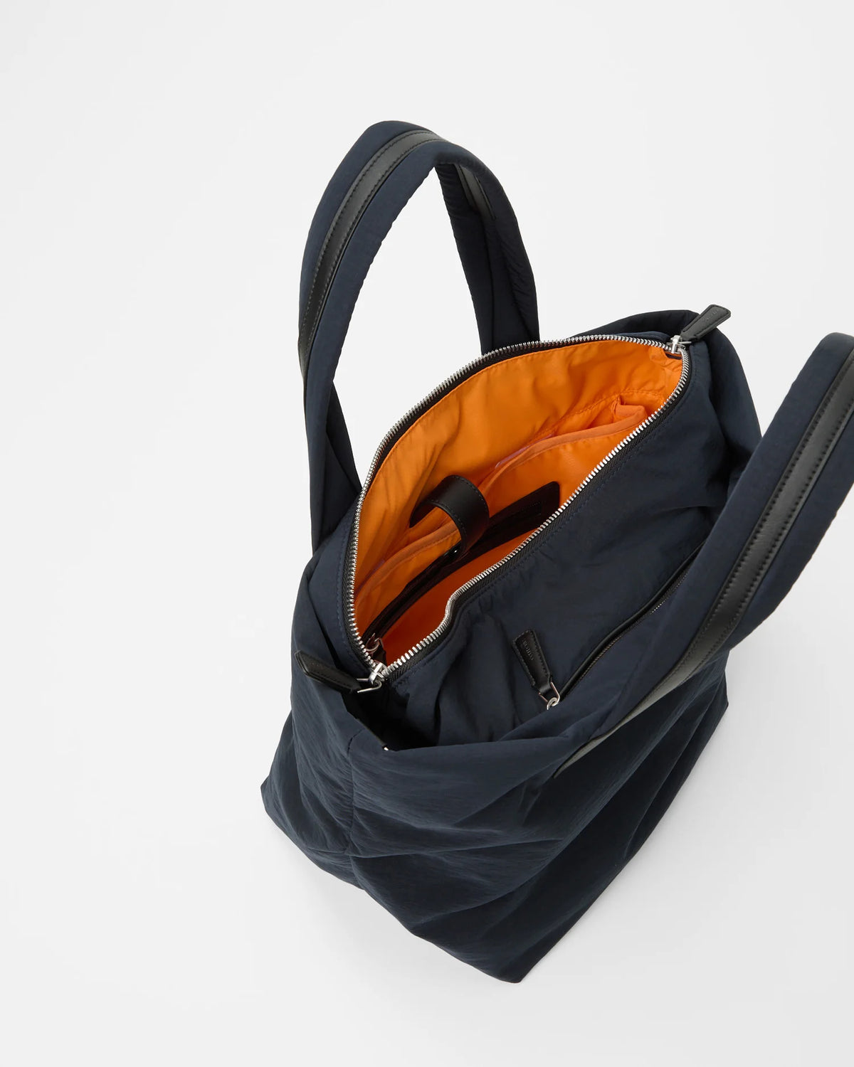 Open Vee Collective Porter Essence Small in Midnight Trench, showing the quilted exterior, top zipper, and orange interior of the Tote bag.