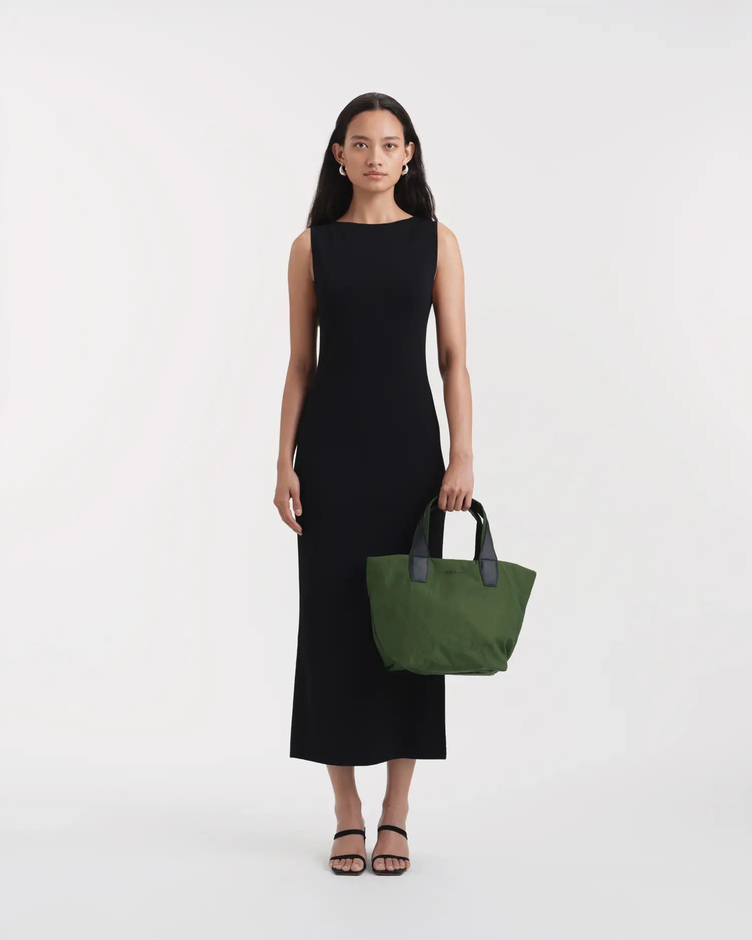 Porter Essence Small Olive Paper bag held by a model in a black dress, showcasing its minimalist design and paper touch material.