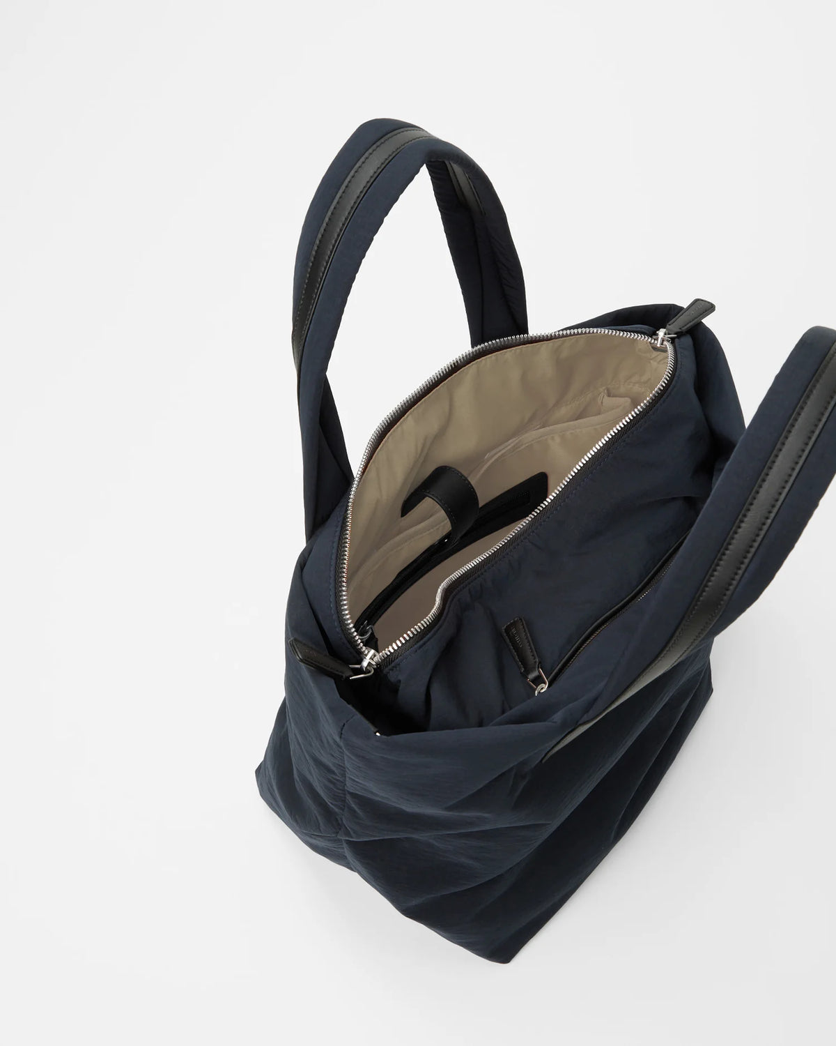 An overhead view of a large Essence Tote bag in a midnight color. The interior features a light-colored lining with a zippered pocket
