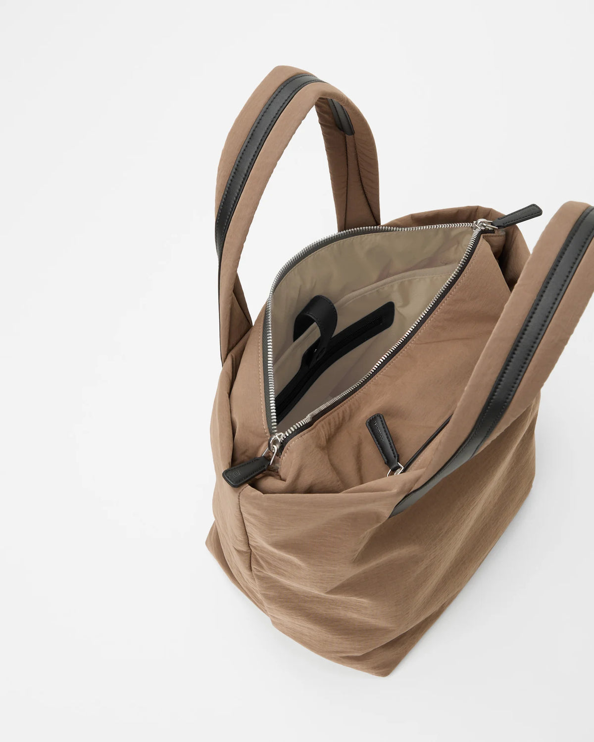 An overhead view of a large Essence Tote bag in a beige color. The interior features a light-colored lining with a zippered pocket
