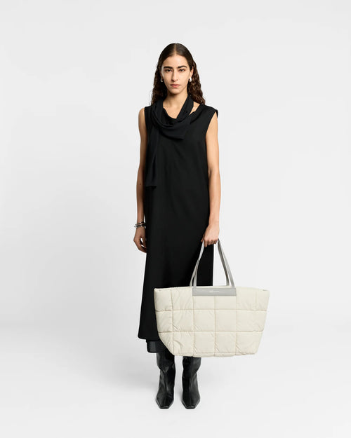 Woman wearing a clean outfit holding the Vee Collective Porter Marché Tote Bag Large in Barely Beige, shown against a clean background.