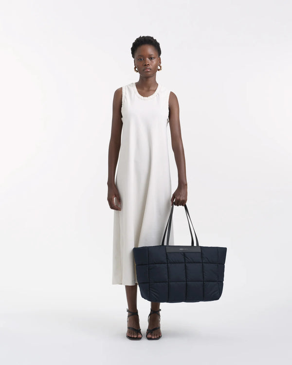 On-body picture of a woman holding the Porter Marché Large Tote Bag in Dark Navy by Vee Collective, wearing a minimalistic outfit against a clean studio background.