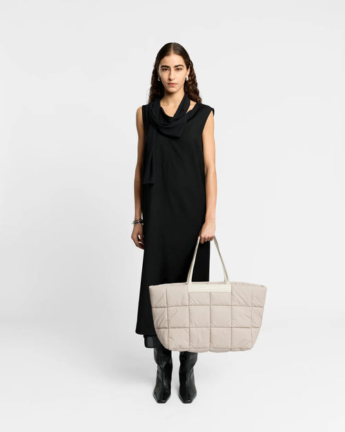 Woman wearing a clean outfit holding the Vee Collective Porter Marché Tote Bag in Soft Taupe, shown against a clean background.
