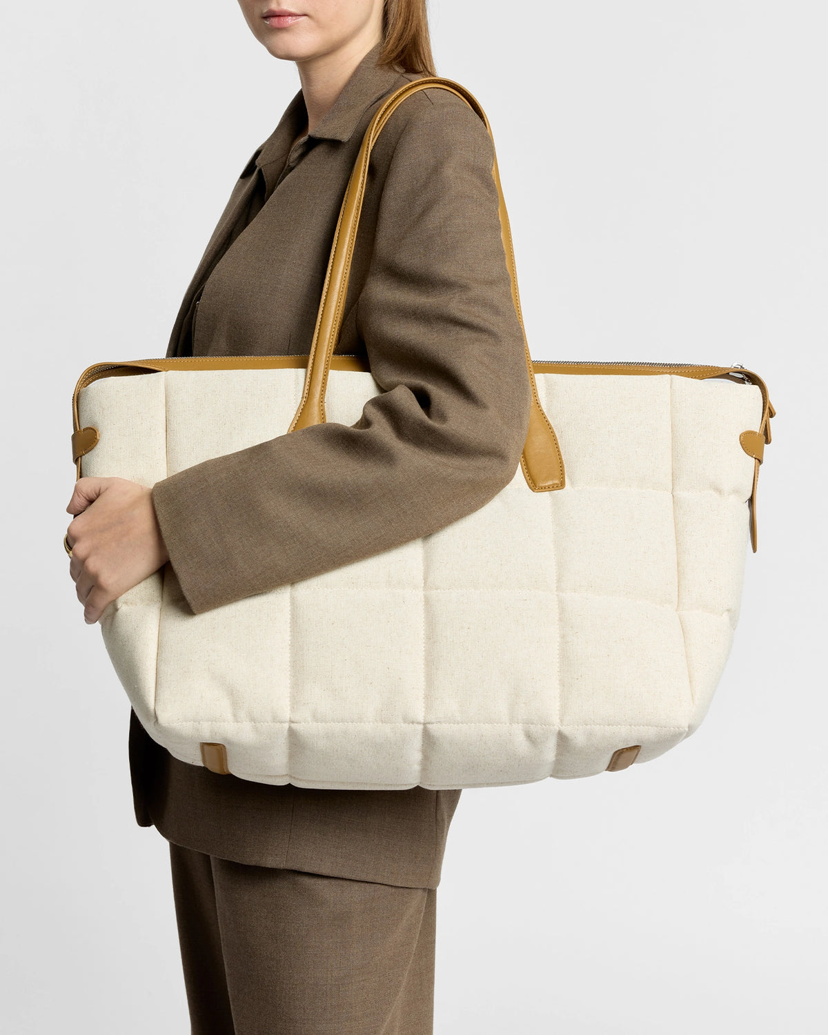 Model carries Tela Tote in natural canvas with tan leather handles