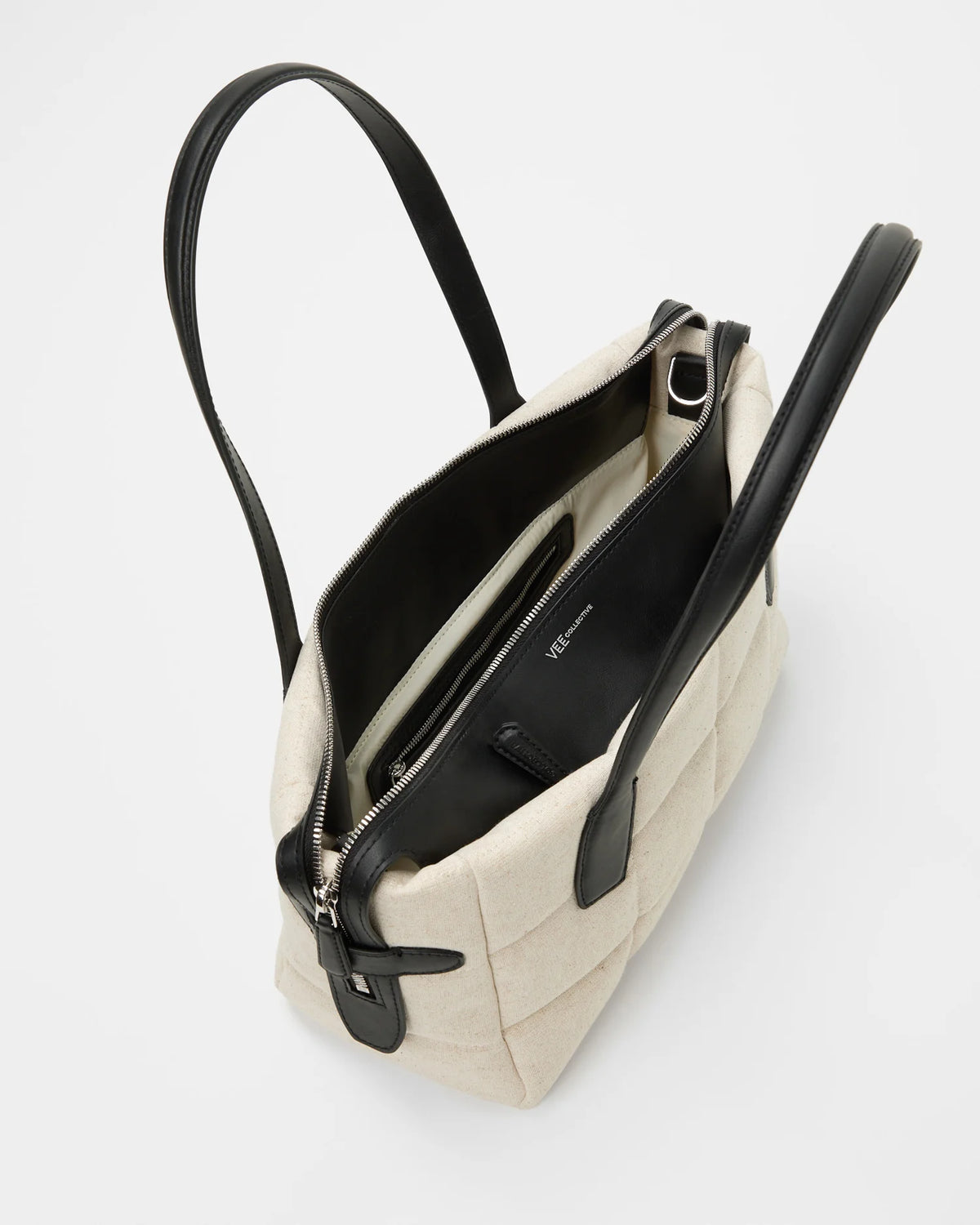 Open Tela Tote in natural canvas with black leather handles showing the zippered top and interior lining