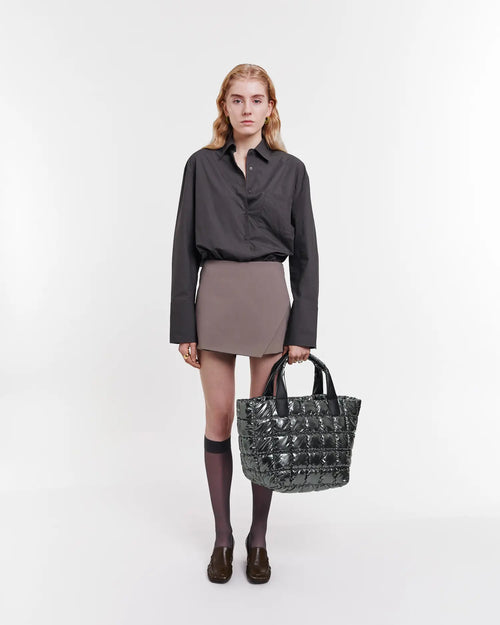 Model wearing a dark grey shirt carries the Gadget Grey Porter Tote by its handles
