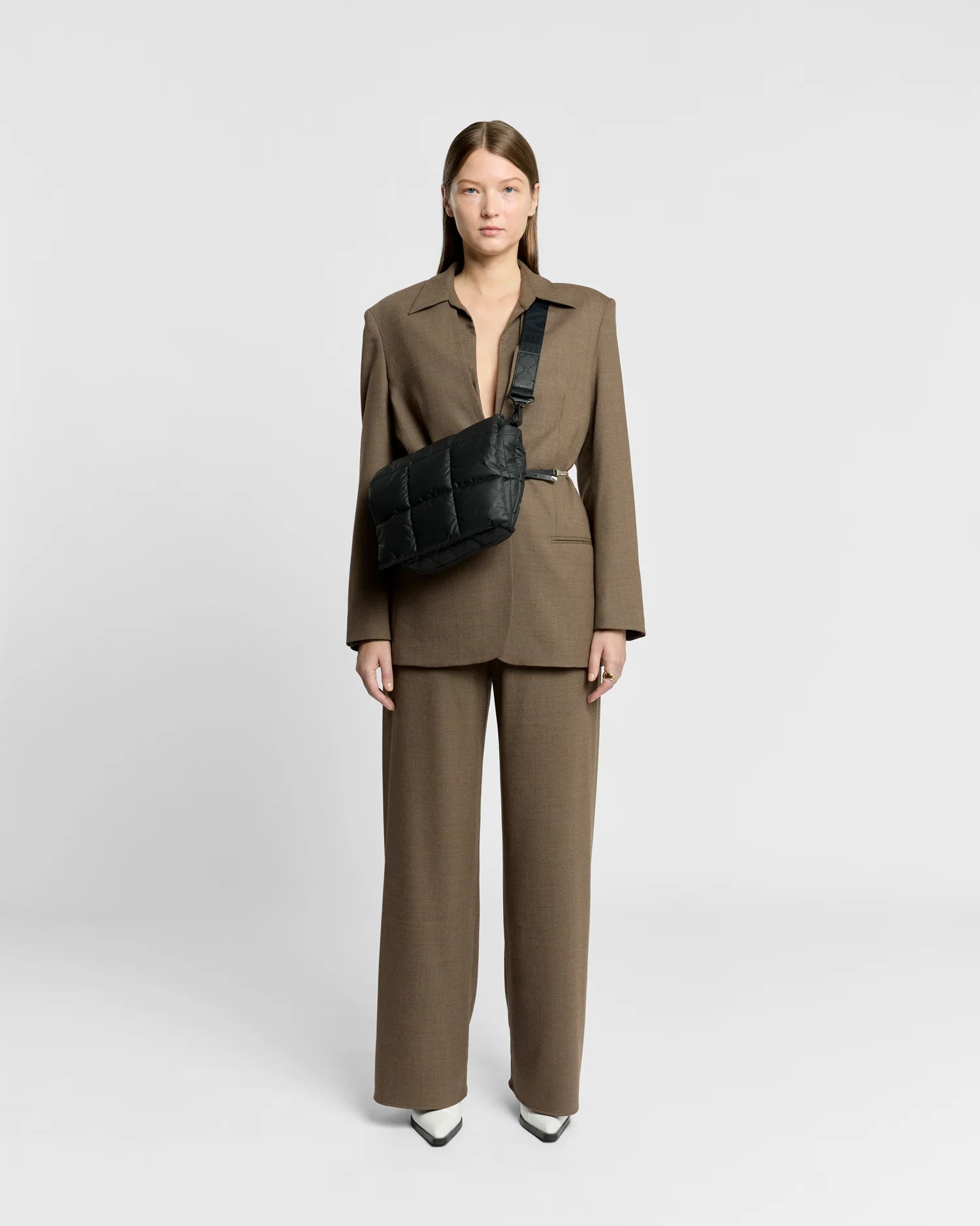 Woman in a minimal, clean outfit carrying the Vee Collective Porter Messenger Bag in Black, shown with its crossbody strap.