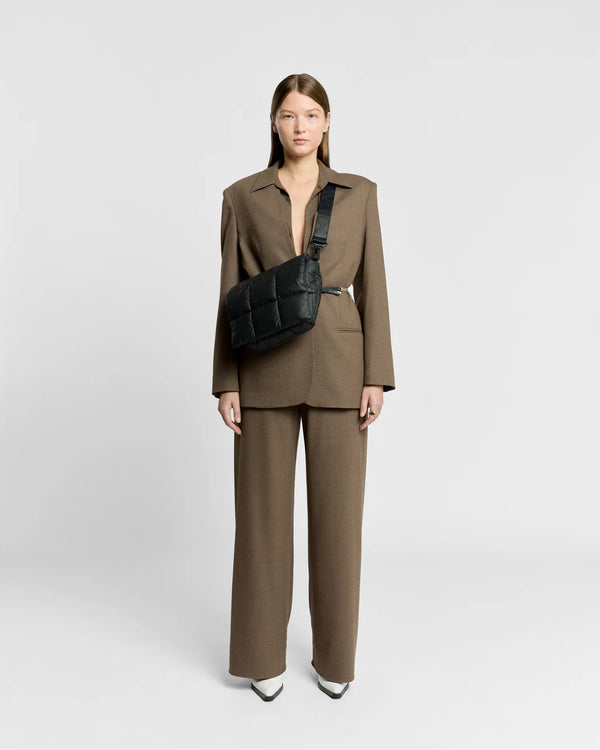 Woman in a minimal, clean outfit carrying the Vee Collective Porter Messenger Bag in Black, shown with its crossbody strap.