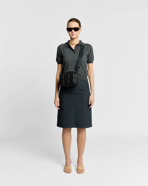 Woman in a minimal, clean outfit carrying the Vee Collective Porter Messenger Mini Bag in Black, shown with its crossbody strap.