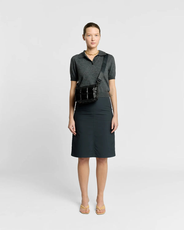 Woman in a minimal, clean outfit carrying the Vee Collective Porter Messenger Mini Bag in Black Vinyl, shown with its crossbody strap.