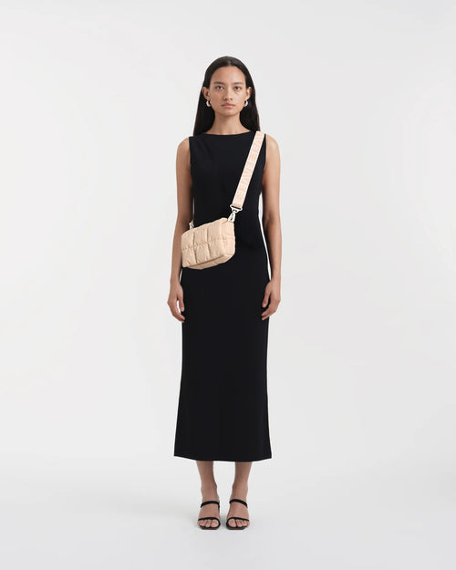 Woman wearing a clean, minimalist outfit, styled with the Vee Collective Porter Messenger Mini Bag in Cameo Rose worn crossbody.