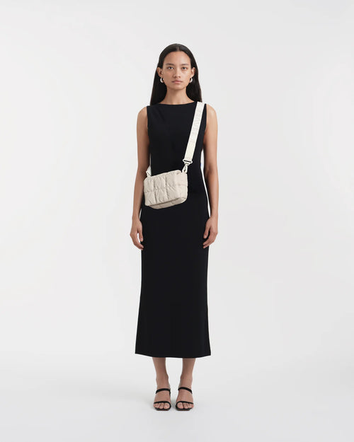 Woman wearing a clean, minimalist outfit, styled with the Vee Collective Porter Messenger Mini Bag in Soft Taupe worn crossbody.
