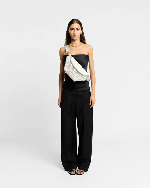 Woman wearing the Porter Sling Bag in Barely Beige by Vee Collective crossbody, styled with a minimalistic outfit against a clean studio background.