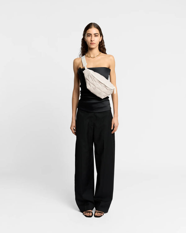 Woman wearing the Porter Sling Bag in Soft Taupe by Vee Collective crossbody, styled with a minimalistic outfit against a clean studio background.