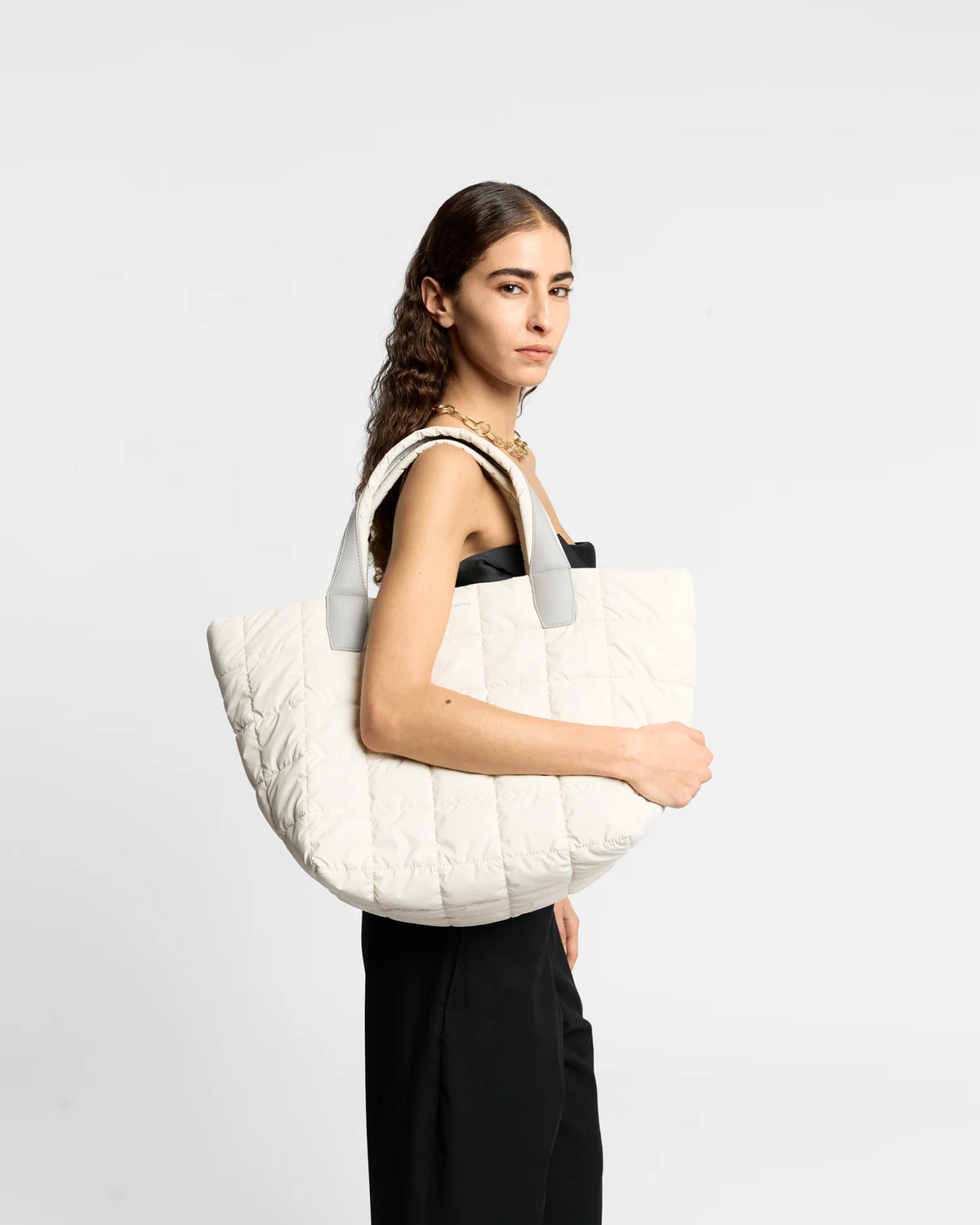 On-body picture of a woman carrying the Medium Porter Tote Bag in Barely Beige by Vee Collective, wearing a minimalistic outfit against a clean studio background.