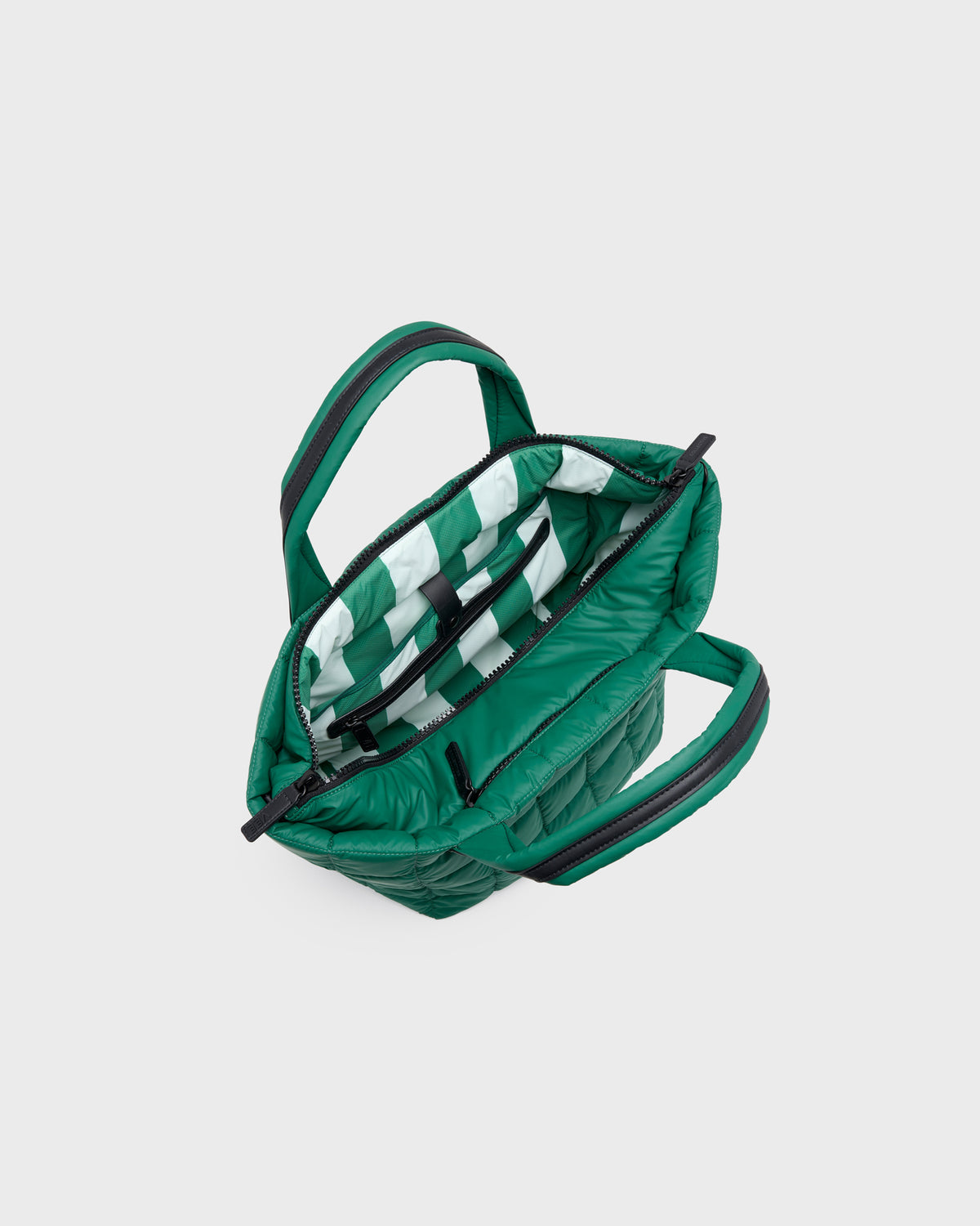 A green quilted puffer handbag shown open from a top-down angle, revealing a green and white striped interior lining and black zipper details, set against a solid light gray background.