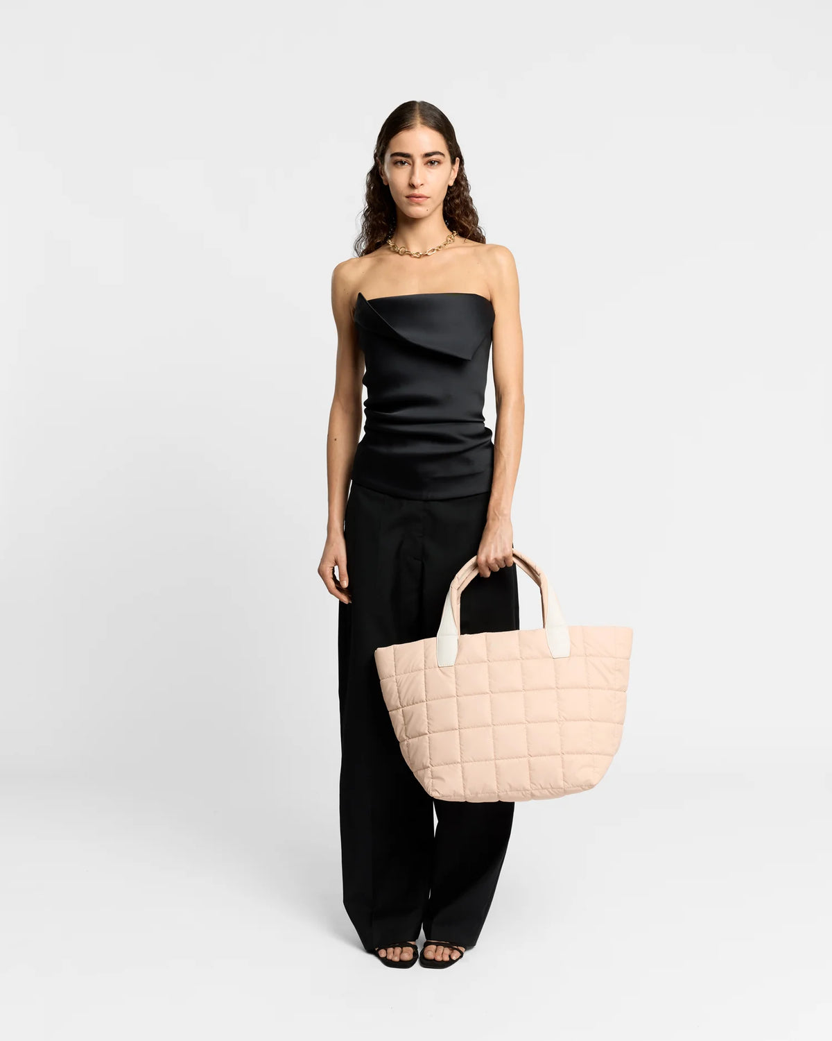On-body picture of a woman holding the Medium Porter Tote Bag in Cameo Rose by Vee Collective, wearing a minimalistic outfit against a clean studio background.