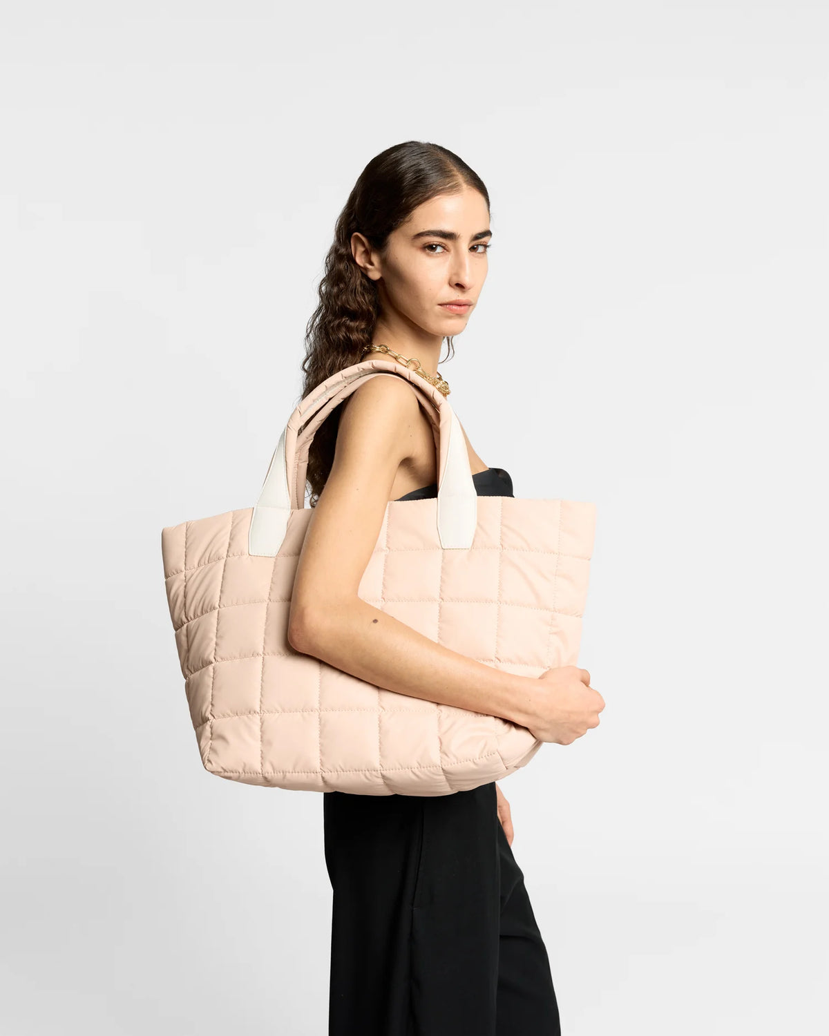 On-body picture of a woman carrying the Medium Porter Tote Bag in Cameo Rose by Vee Collective, wearing a minimalistic outfit against a clean studio background.