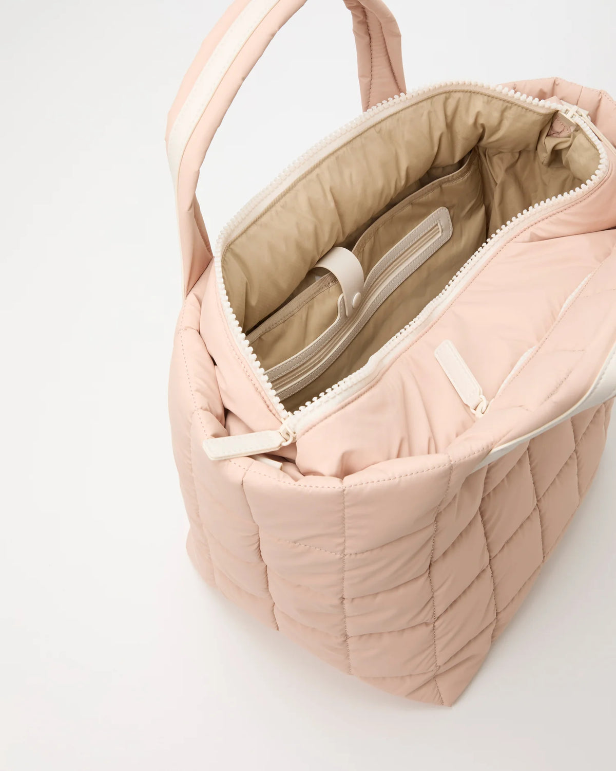 Open Vee Collective Porter Tote Bag Medium in Cameo Rose, showing the quilted exterior, top zipper, and interior compartments of the tote bag.