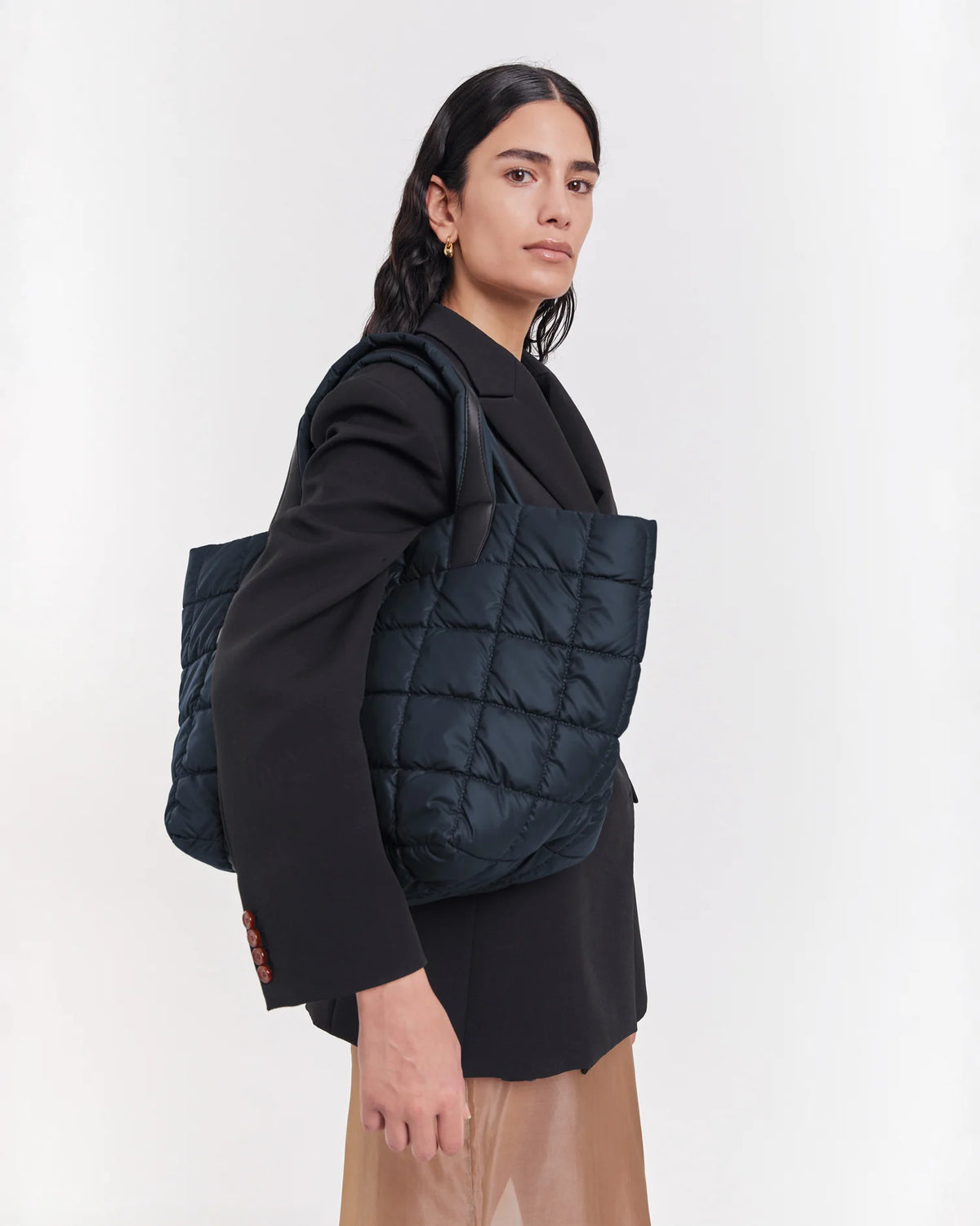 On-body picture of a woman Carrying the Medium Porter Tote Bag in Dark Navy by Vee Collective, wearing a minimalistic outfit against a clean studio background.