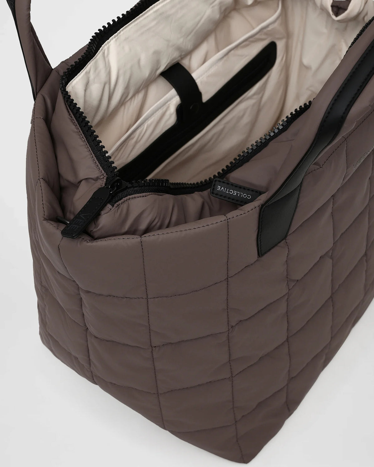 A close-up photo of an open Porter Tote in mink bag featuring black zippers and a light beige interior lining, set against a white background.
