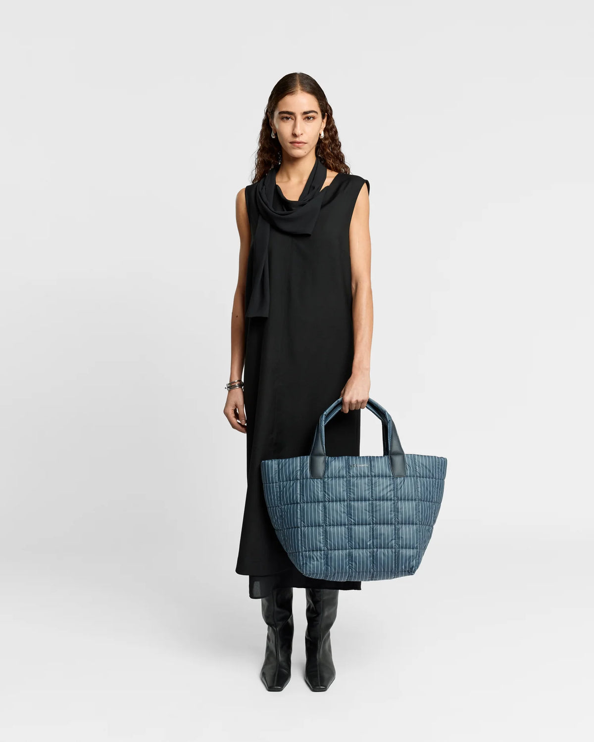 On-body picture of a woman holding the Medium Porter Tote Bag in Pinstripe by Vee Collective, wearing a minimalistic outfit against a clean studio background.