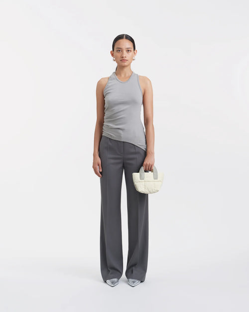 Woman wearing a clean outfit holding the Vee Collective Porter Tote Bag Micro in Barely Beige, shown against a clean background.