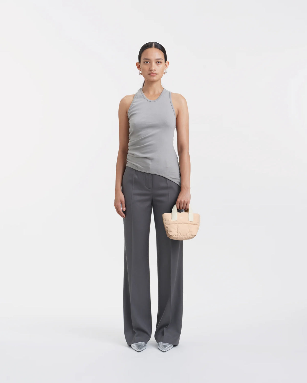 Woman wearing a clean outfit holding the Vee Collective Porter Tote Bag Micro in Cameo Rose, shown against a clean background.