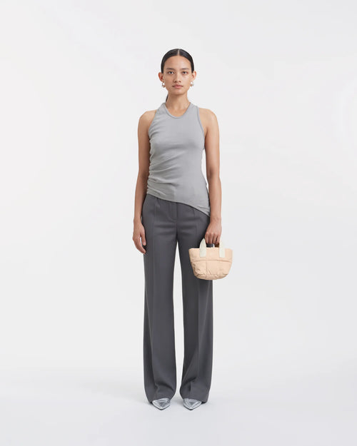 Woman wearing a clean outfit holding the Vee Collective Porter Tote Bag Micro in Cameo Rose, shown against a clean background.