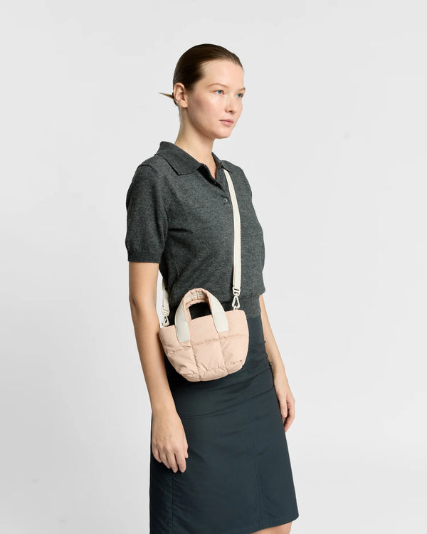 On-body picture of a woman carrying the Micro Porter Tote Bag in Cameo Rose by Vee Collective, styled crossbody with the attachable strap, wearing a minimalistic outfit against a clean studio background.