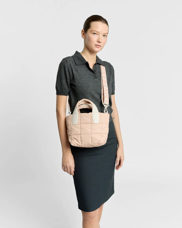On-body picture of a woman carrying the Mini Porter Tote Bag in Cameo Rose by Vee Collective, styled crossbody with the attachable strap, wearing a minimalistic outfit against a clean studio background.
