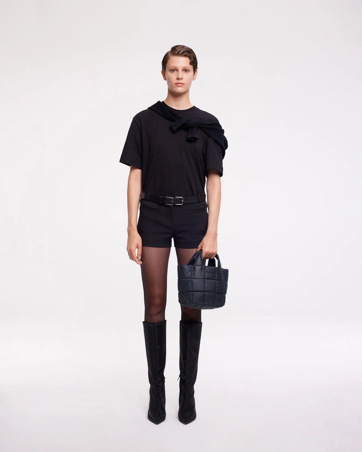 On-body picture of a woman holding the Mini Porter Tote Bag in Dark Navy by Vee Collective, wearing a minimalistic outfit against a clean studio background.
