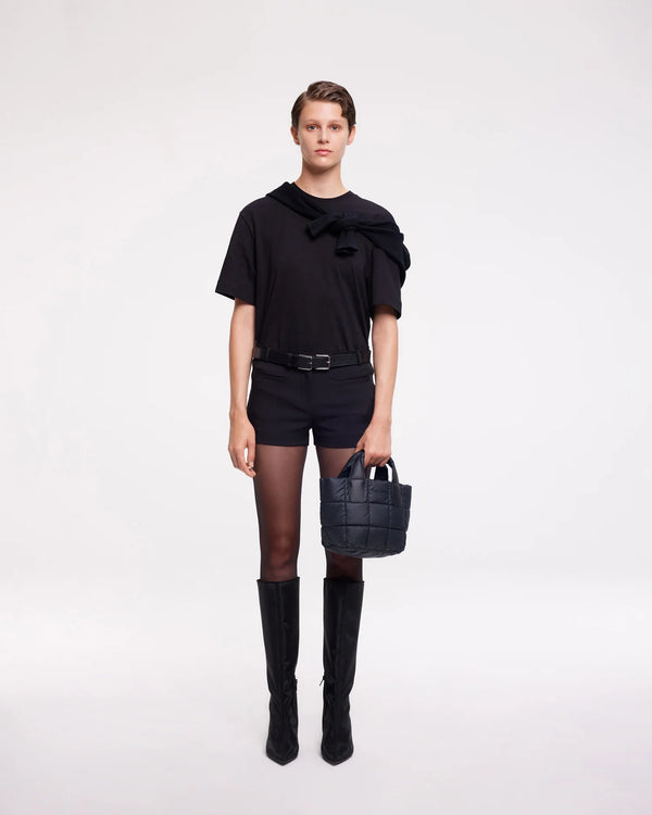 On-body picture of a woman holding the Mini Porter Tote Bag in Dark Navy by Vee Collective, wearing a minimalistic outfit against a clean studio background.