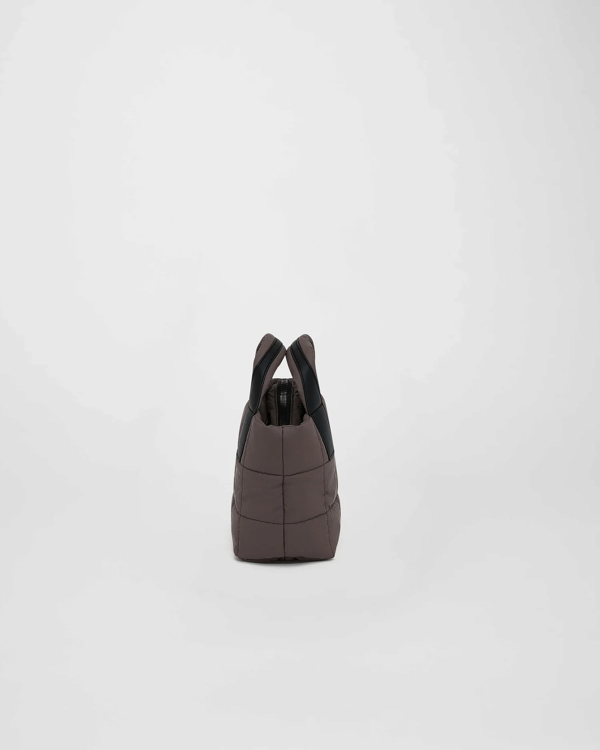 A picture featuring the side view of a small Porter Tote Bag in mink with a puffy square pattern, two sturdy handles, and a zippered top on a white background